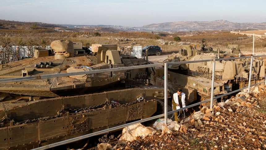 An Israeli soldier walks past tanks deployed near the Israel-Syria border in the Israeli-occupied Golan Heights on December 8, 2024.