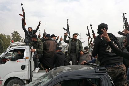 People wave guns in the air as they gather to celebrate the fall of the Syrian regime in Umayyad Square on Sunday in Damascus, Syria.