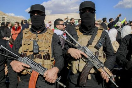 Armed individuals in tactical gear stand amidst a crowd in Damascus, Syria, on December 13.