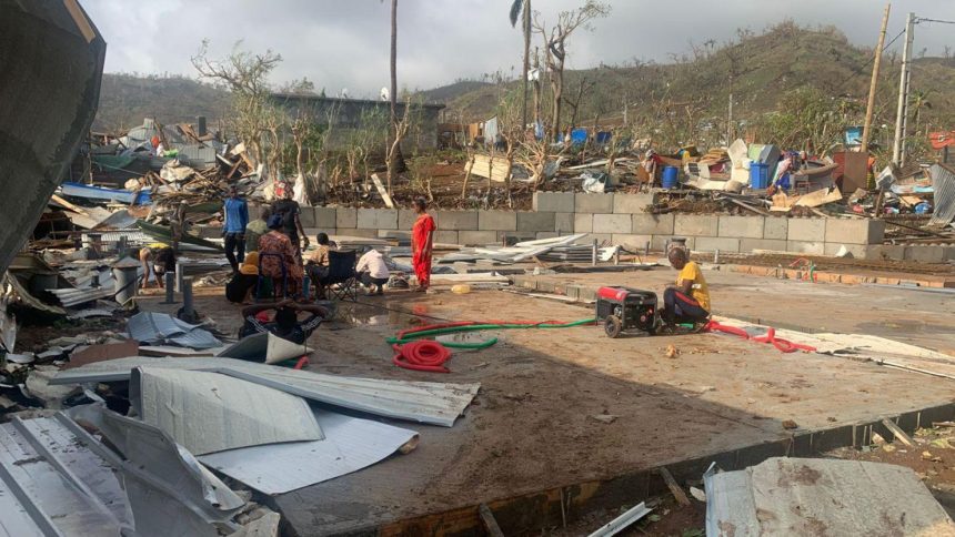 Residents in France's Indian Ocean territory of Mayotte sit among piles of debris of metal sheets and wood on December 15 after homes were destroyed by Cyclone Chido.