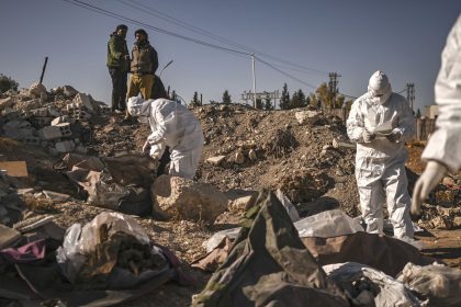 Members of Syria's White Helmets civil defense collect human remains at a mass grave that was uncovered in Damascus on Monday.