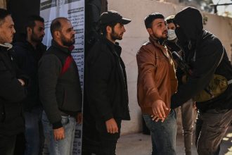 Syrian soldiers and police officers line up to register at a center in Daraa, southern Syria, and surrender their weapons on December 17.