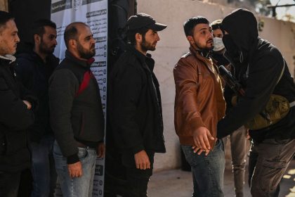 Syrian soldiers and police officers line up to register at a center in Daraa, southern Syria, and surrender their weapons on December 17.