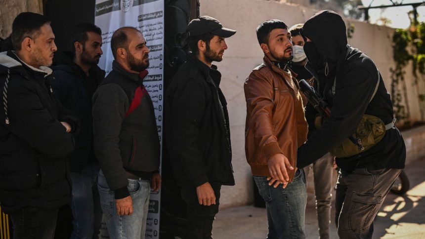 Syrian soldiers and police officers line up to register at a center in Daraa, southern Syria, and surrender their weapons on December 17.