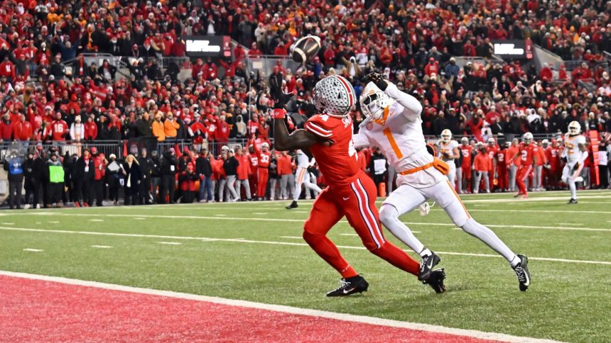 Jeremiah Smith of the Ohio State Buckeyes catches a touchdown pass ahead of Rickey Gibson II of the Tennessee Volunteers during the first quarter at Ohio Stadium.