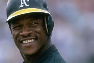 Outfielder Rickey Henderson of the Oakland Athletics on the field smiling during a game at the Oakland Coliseum in Oakland, California.