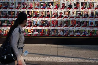 A woman passes posters of hostages kidnapped during the deadly October 7 attack on Israel by Hamas, in Tel Aviv, Israel, on August 21, 2024.