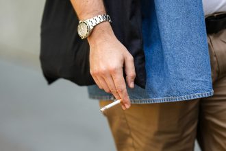 An attendee at a show holds a cigarette during Milan Fashion Week in 2022.