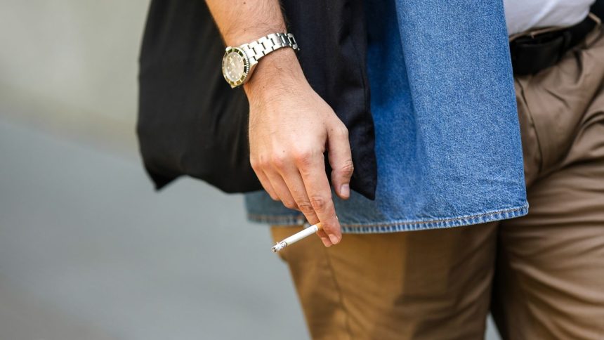 An attendee at a show holds a cigarette during Milan Fashion Week in 2022.