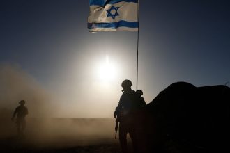 Soldiers with the Israel Defense Forces (IDF) stand near a military vehicle on March 4, 2024 in southern Israel near the border with Gaza.