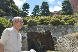 Shigemi Fukahori poses in front of the former bell tower of the Urakami Cathedral in Nagasaki, Nagasaki Prefecture, on July 17, 2013.