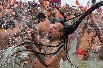 Naga Sadhus take a holy dip in the sacred waters of the Triveni Sangam, the confluence of three holy rivers on the first royal bathing day of the Kumbh Mela on Tuesday, January 14.