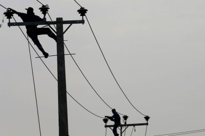 People pull electric cables on top of electricity posts in Piliyandala, Sri Lanka on November 29, 2016.