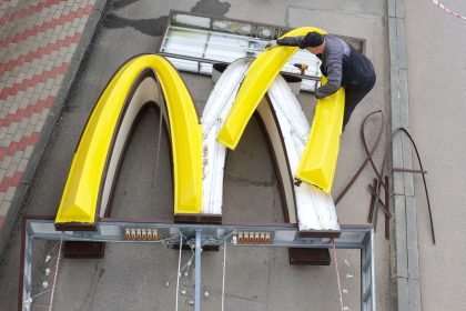 A worker is removing the logo signage from a McDonald's in the Russian town of Kingisepp in June 2022.