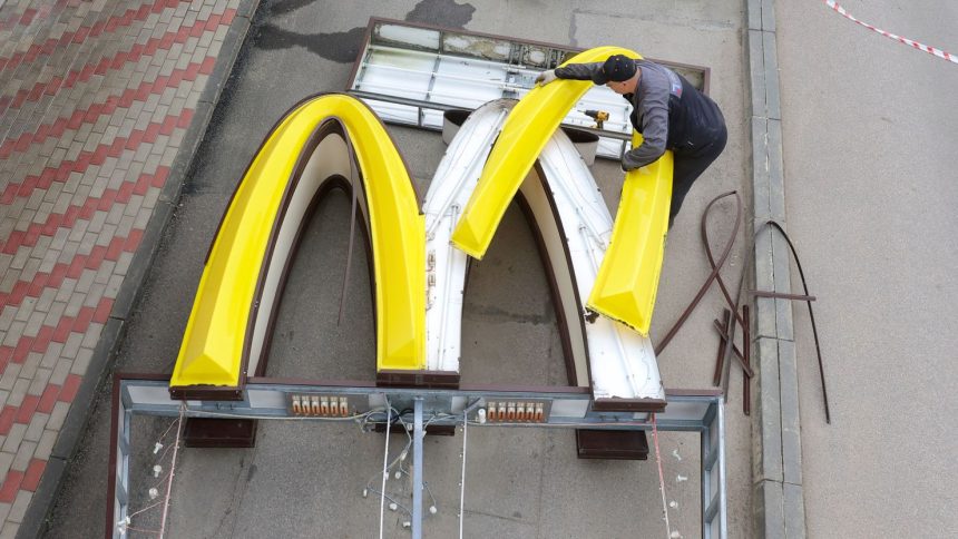 A worker is removing the logo signage from a McDonald's in the Russian town of Kingisepp in June 2022.