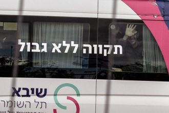 Released hostage Eli Sharabi gestures from behind the window to people who came to show support as he arrived at Sheba Medical Center for treatment on February 8, 2025.