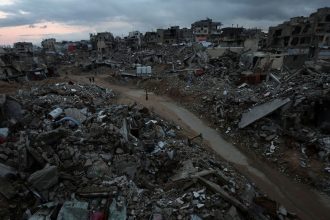 Palestinians walk among the rubble of destroyed buildings in Khan Younis, in southern Gaza, on February 24, 2025.