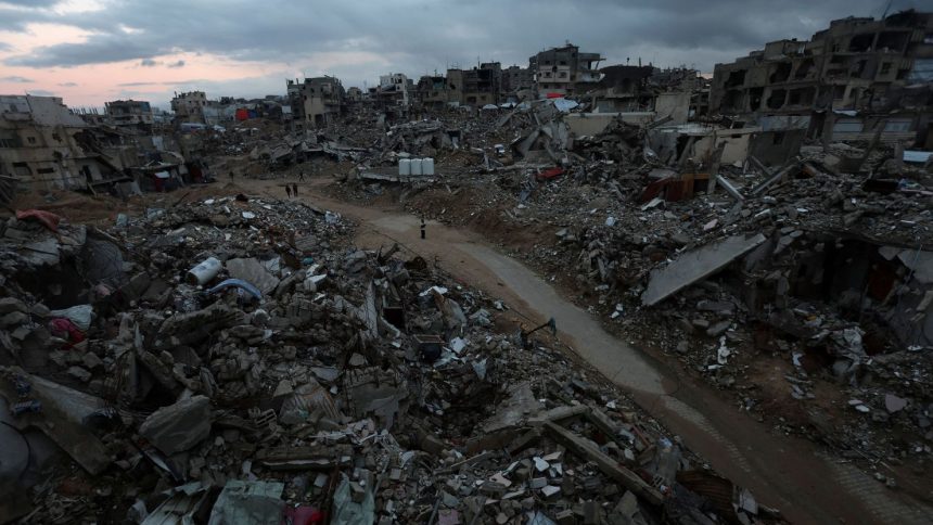 Palestinians walk among the rubble of destroyed buildings in Khan Younis, in southern Gaza, on February 24, 2025.