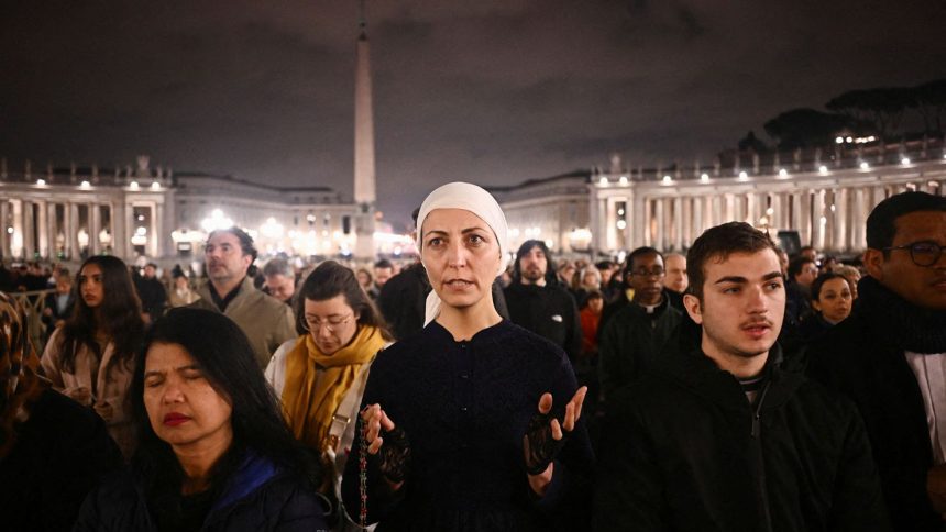 People take part in a prayer service at St. Peter's Square on February 25 2025, as Pope Francis continues his hospitalization.