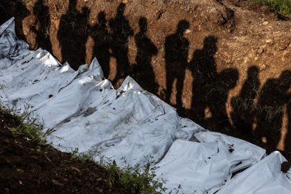 Residents cast their shadows as they observe members of the Congolese Red Cross conduct a mass burial for victims of the clashes in eastern Democratic Republic of Congo at Musigiko cemetery in Bukavu on February 20, 2025.