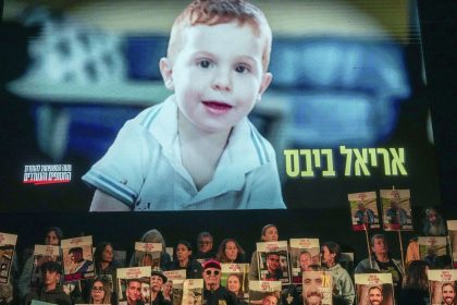 Demonstrators hold portraits of hostages held by Hamas in the Gaza as a video featuring Ariel Bibas plays behind them during a protest in Tel Aviv on January 18, 2025.