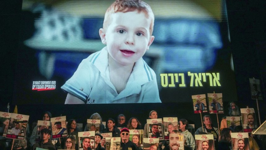 Demonstrators hold portraits of hostages held by Hamas in the Gaza Strip as a video featuring Ariel Bibas plays behind them during a protest in Tel Aviv on January 18.