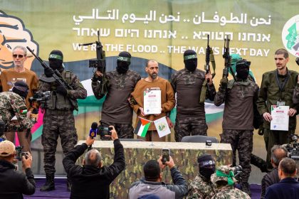 Israeli hostages Ohad Ben Ami, Eli Sharabi and Or Levy stand next to Hamas fighters on a stage before being handed over to the Red Cross in Deir al-Balah, Gaza, on Saturday.