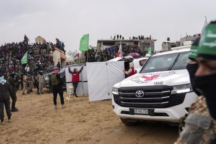 Palestinians gather as Hamas militants hand over coffins containing four bodies to the Red Cross in Khan Younis, southern Gaza Strip, Thursday, Feb. 20, 2025.  Israel has identified three of the bodies as hostages and said the other was of an unknown person. (AP Photo/Abdel Kareem Hana)