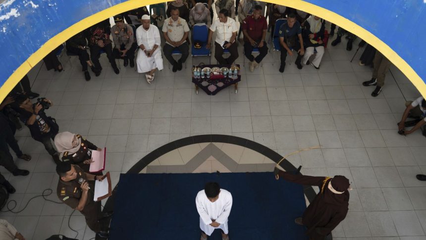 A Shariah Law official uses a rattan cane to whip one of two men convicted of gay sex in Banda Aceh, Aceh province, Indonesia, Thursday, Feb. 27, 2025.