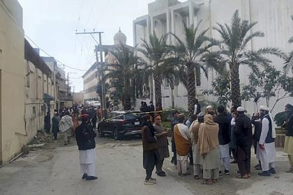 People gather near the site of a deadly suicide bombing in northwestern Pakistan, on February 28, which tore through a mosque at a pro-Taliban seminary.