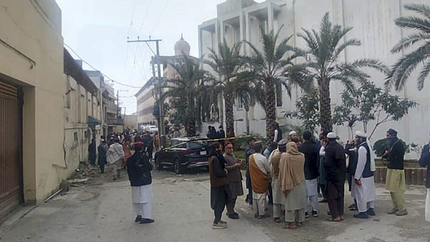 People gather near the site of a deadly suicide bombing in northwestern Pakistan, on February 28, which tore through a mosque at a pro-Taliban seminary.