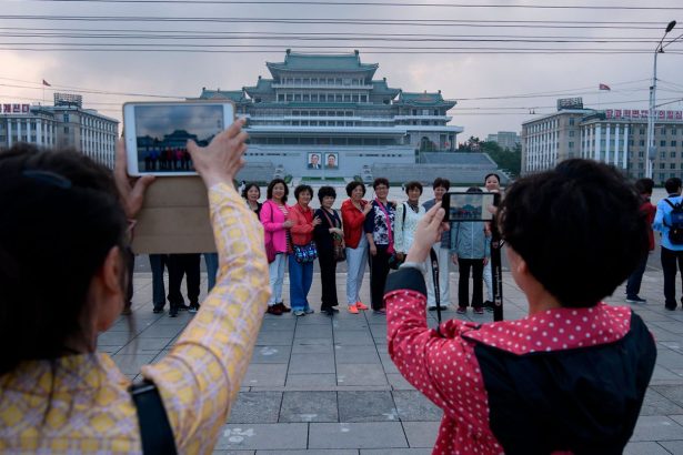 Chinese tourists pose for photos on Kim Il Sung square in Pyongyang on June 19, 2019.