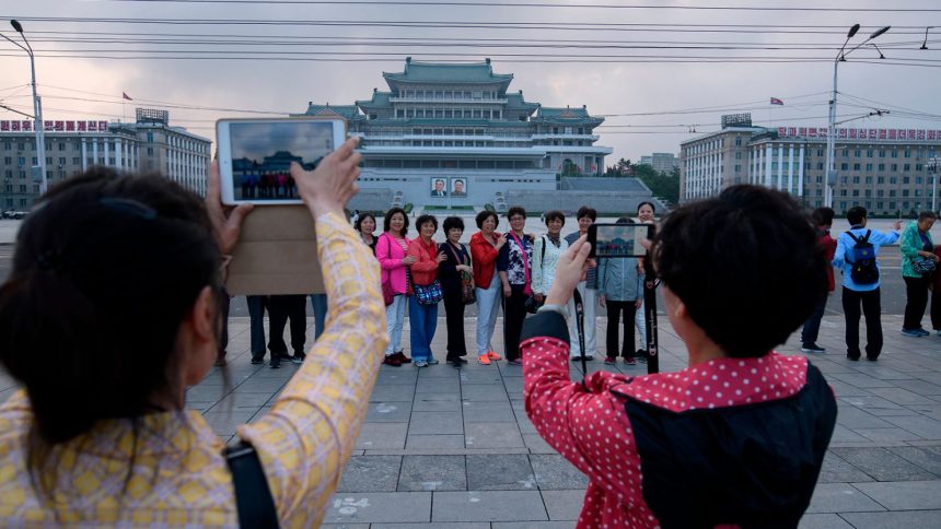 Chinese tourists pose for photos on Kim Il Sung square in Pyongyang on June 19, 2019.