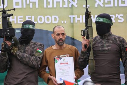 Hamas militants stand next to Eli Sharabi as he is handed to the Red Cross in Deir al-Balah on Saturday.