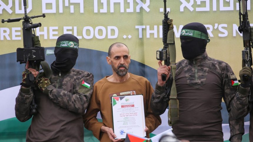 Hamas militants stand next to Eli Sharabi as he is handed to the Red Cross in Deir al-Balah on Saturday.