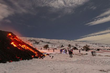 A crowd of tourists gather to witness a lava flow descend down the southwestern flank of Mount Etna.