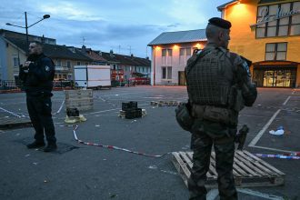 A police officer and a military stand guard at the site of a bladed weapon attack where a man is suspected of killing one person and wounding two municipal police officers in Mulhouse, eastern France on February 22, 2025.