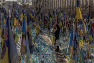 Visitors stand near a makeshift memorial paying tribute to Ukrainian and foreign fighters at the Independence Square in Kyiv, on February 23, 2025, ahead of the third anniversary of Russia's invasion of Ukraine.