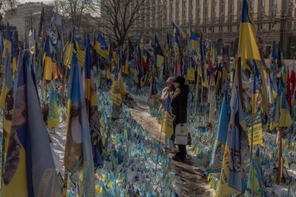 Visitors stand near a makeshift memorial paying tribute to Ukrainian and foreign fighters at the Independence Square in Kyiv, on February 23, 2025, ahead of the third anniversary of Russia's invasion of Ukraine.