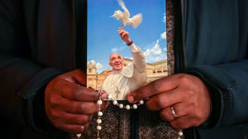 A priest holds a photograph of Pope Francis during the nightly Rosary prayer service in St. Peter's Square on March 6.