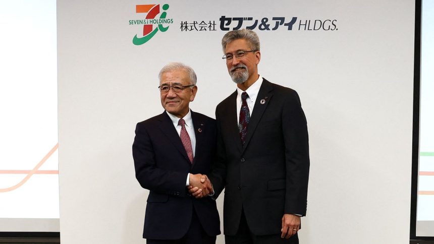 Outgoing Seven & I Holdings CEO Ryuichi Isaka (left) shakes hands with incoming CEO Stephen Dacus (right) at a press conference in Tokyo.