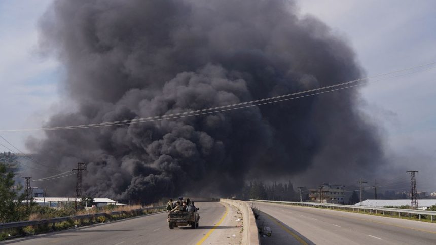 Smoke rises while members of the Syrian forces ride on a vehicle as they battle against an insurgency by fighters loyal to ousted leader Bashar al-Assad's Alawite sect, in Latakia, Syria, on March 7.