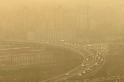 Seen through a glass window, cars drive along a highway during a dust storm amid heavy pollution in Beijing, on March 10, 2023.