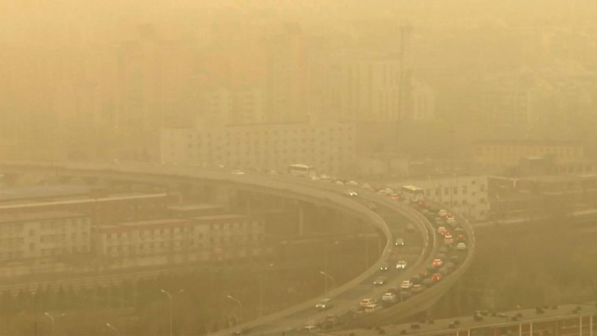 Seen through a glass window, cars drive along a highway during a dust storm amid heavy pollution in Beijing, on March 10, 2023.