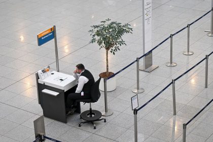 An airport employee sits in front of an empty check-in counter at Terminal 2 of the Munich Airport, in Munich, Germany, on March 10, 2025.