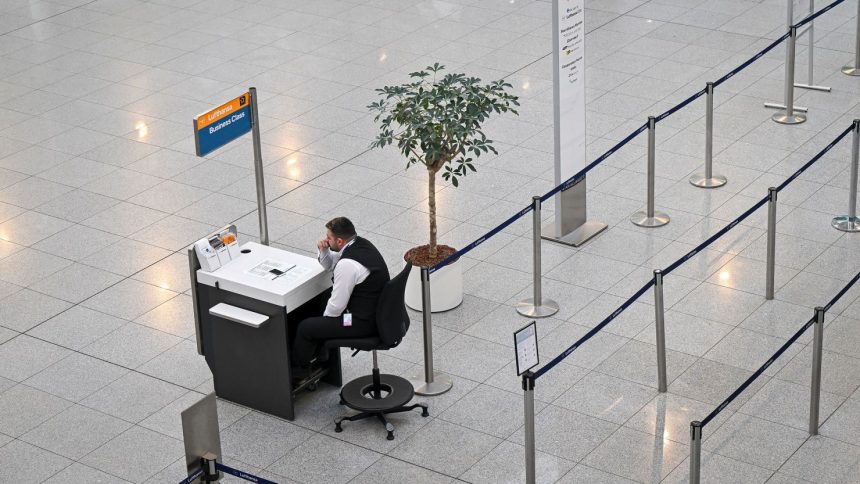 An airport employee sits in front of an empty check-in counter at Terminal 2 of the Munich Airport, in Munich, Germany, on March 10, 2025.