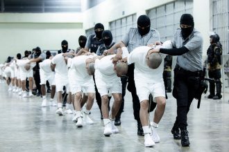 In this photo provided by El Salvador's presidential press office, prison guards transfer deportees from the U.S., alleged to be Venezuelan gang members, to the Terrorism Confinement Center in Tecoluca, El Salvador, Sunday, March 16, 2025.