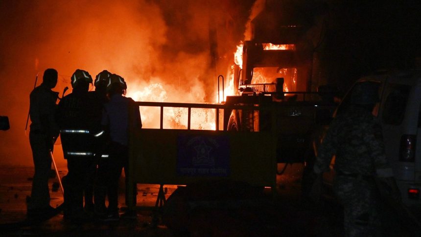 Policemen watch as vehicles are torched during clashes sparked by protests demanding the removal of the tomb of 17th-century Muslim Mughal ruler Aurangzeb, in Nagpur, India, on Monday, March 17, 2025.