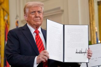 President Donald Trump holds up a signed executive order at an education event in the East Room of the White House in Washington, Thursday, March 20, 2025.