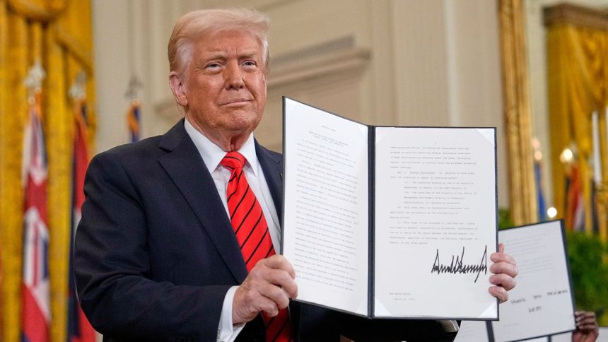 President Donald Trump holds up a signed executive order at an education event in the East Room of the White House in Washington, Thursday, March 20, 2025.